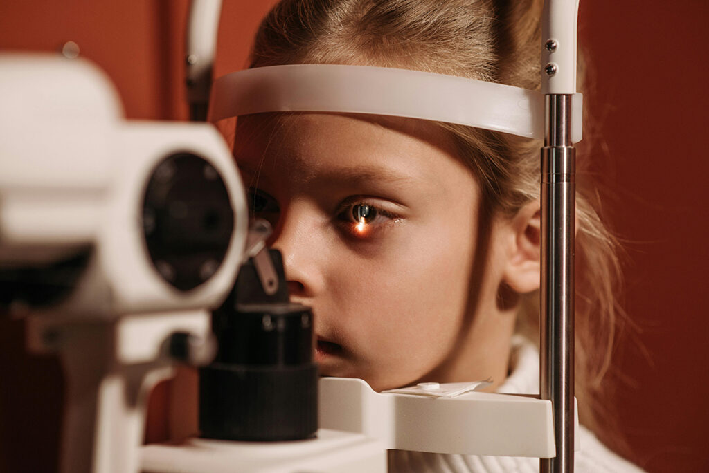 Young girl having her eyes examined. A light is on her eye.